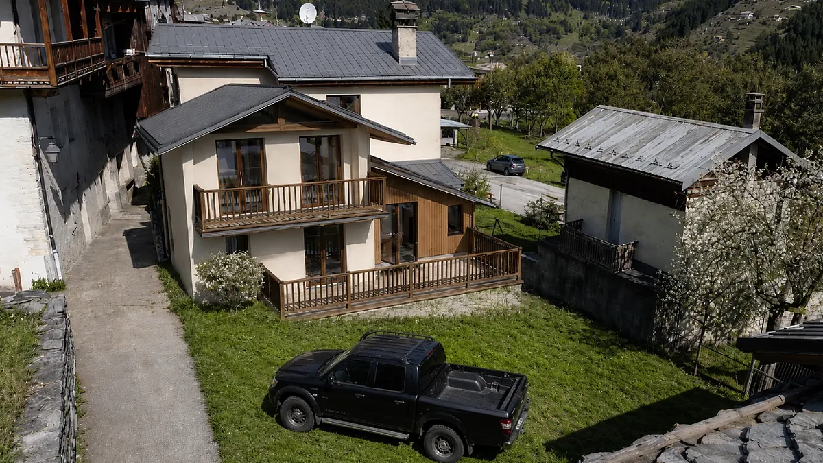 The same Savoie plot after works, with the finished chalet, timber balconies and terrace